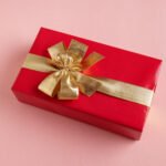 Giftbox with golden ribbon on pink