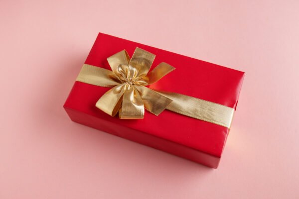 Giftbox with golden ribbon on pink